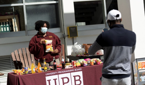 Student hands out items behind a table.
