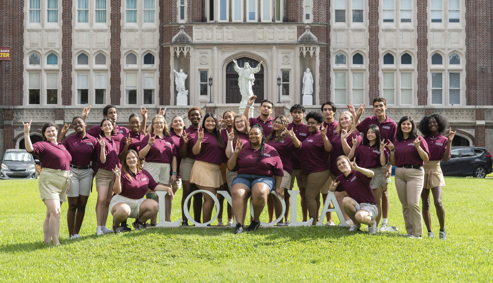 Students holding the "Wolf Hand" in front of Marquette. 