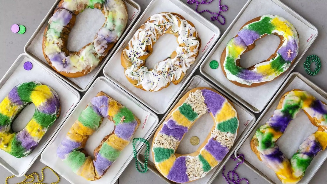 An array of purple, yellow, and green decorated king cakes in their boxes waiting to be eaten!
