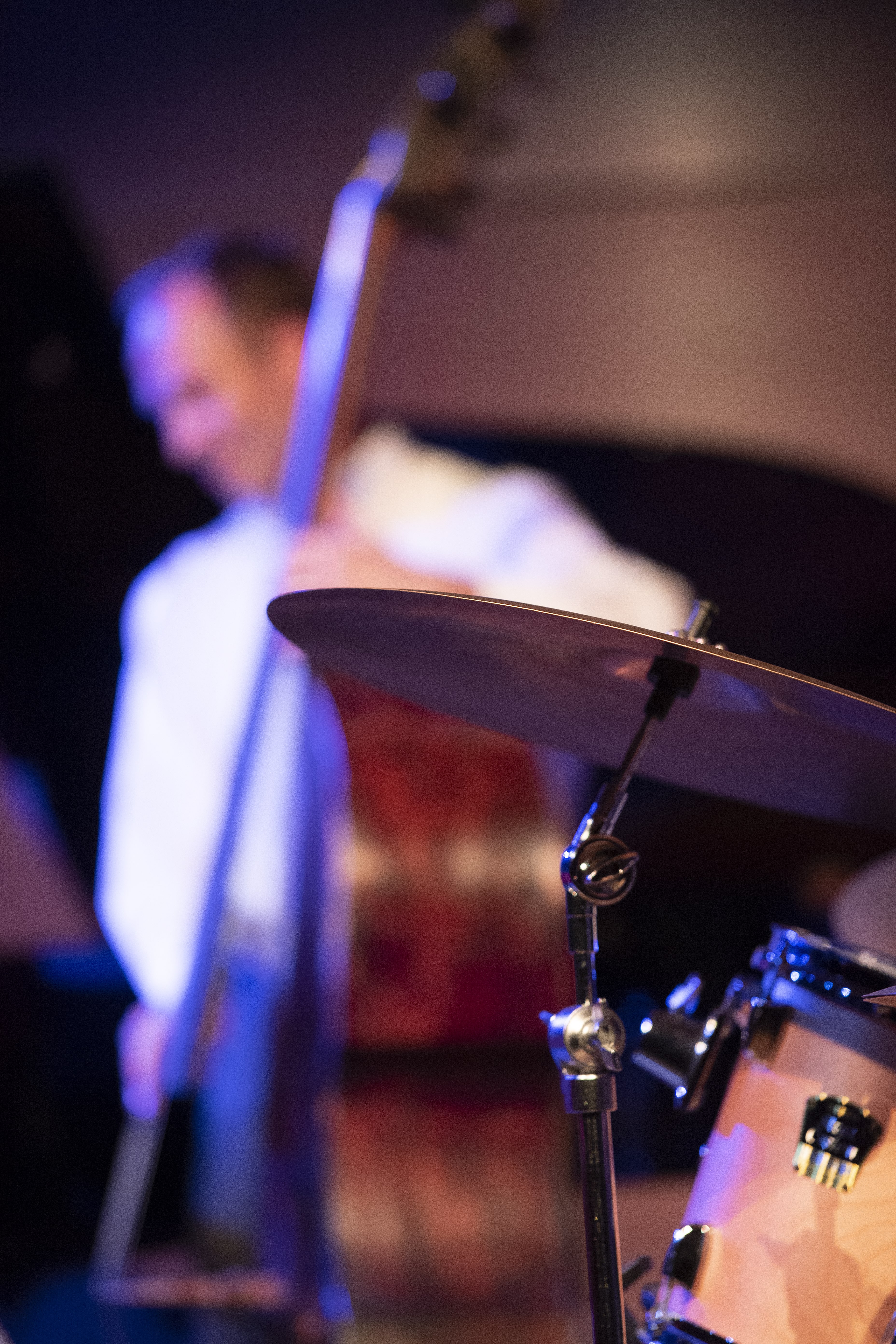 An upright bass player playing in the background, with a jazz drum kit in the foreground.