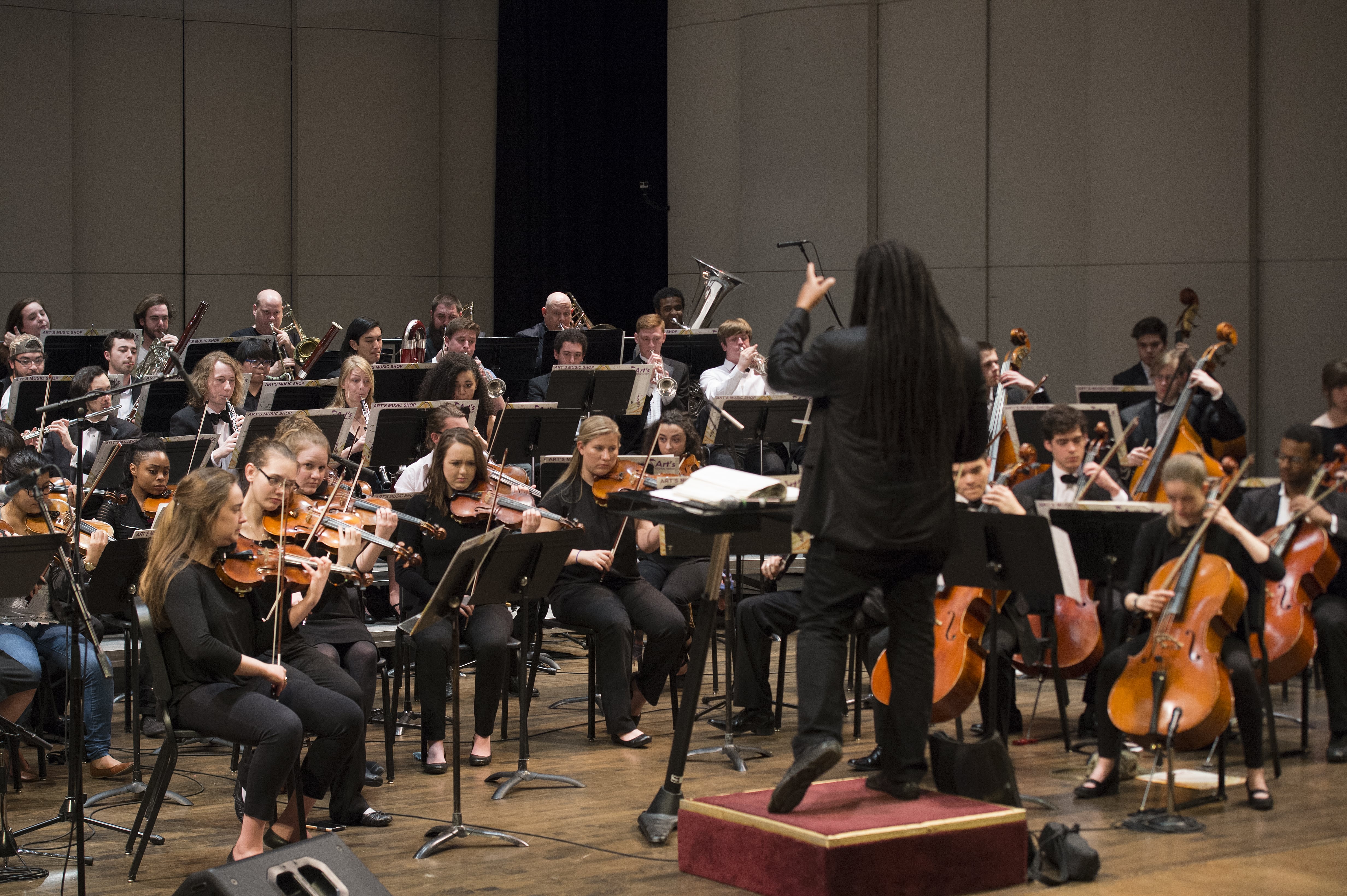 A photograph of Dr. Jean Montès leading a performance of the Loyola Symphony Orchestra.