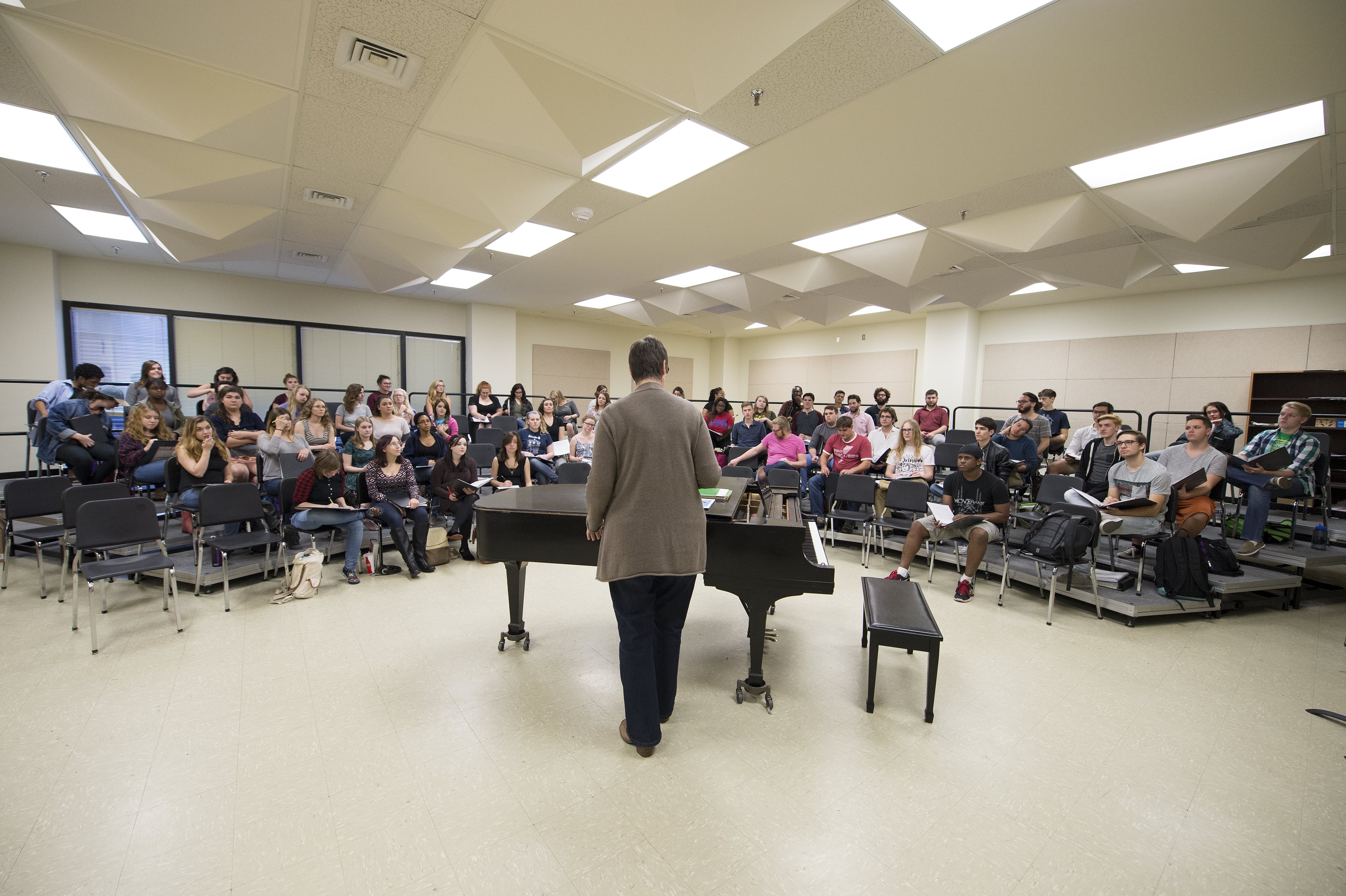A wide shot of a large Loyola choir rehearsing in the choir room.