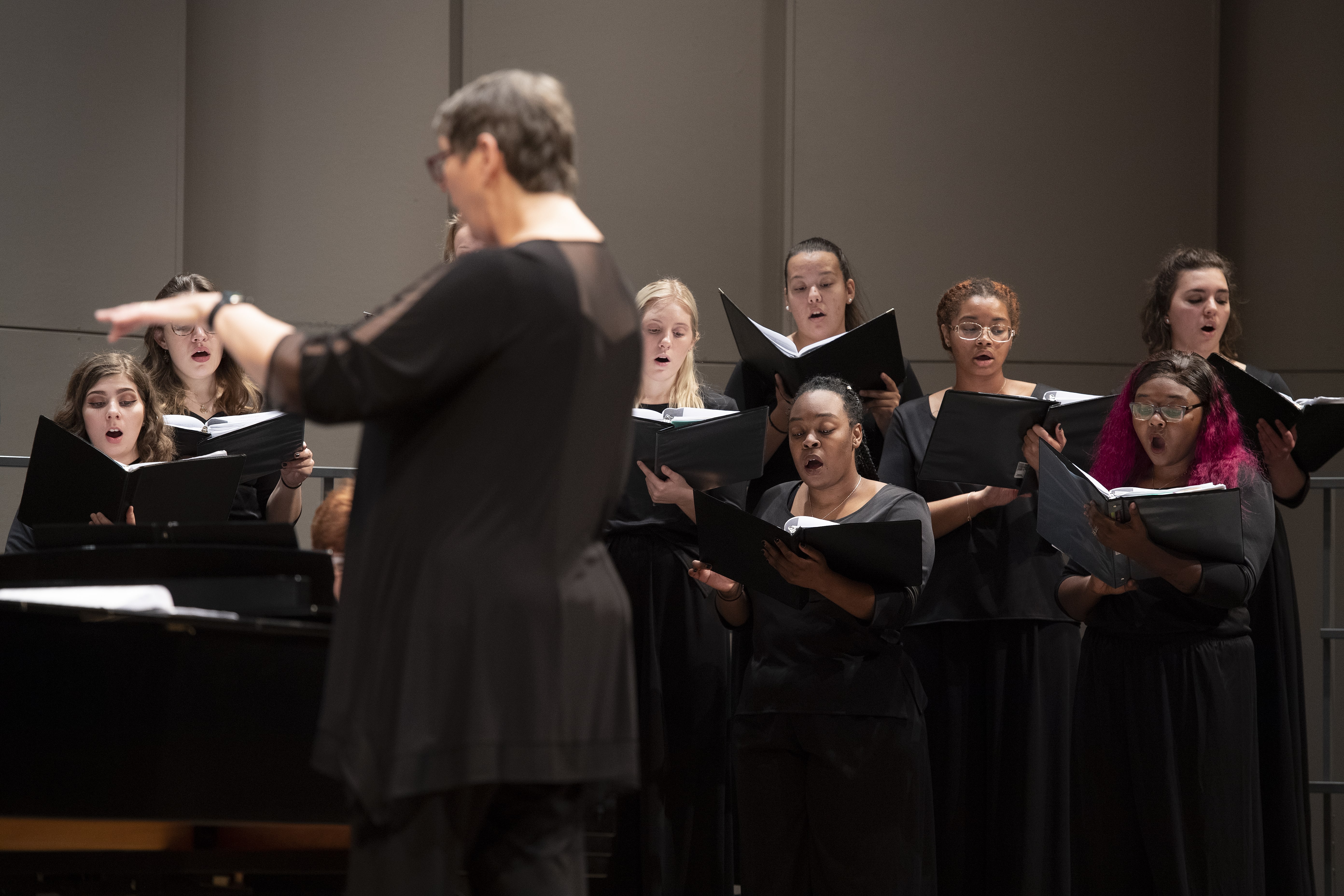 A shot of a Loyola choir singing, taken from behind the director.