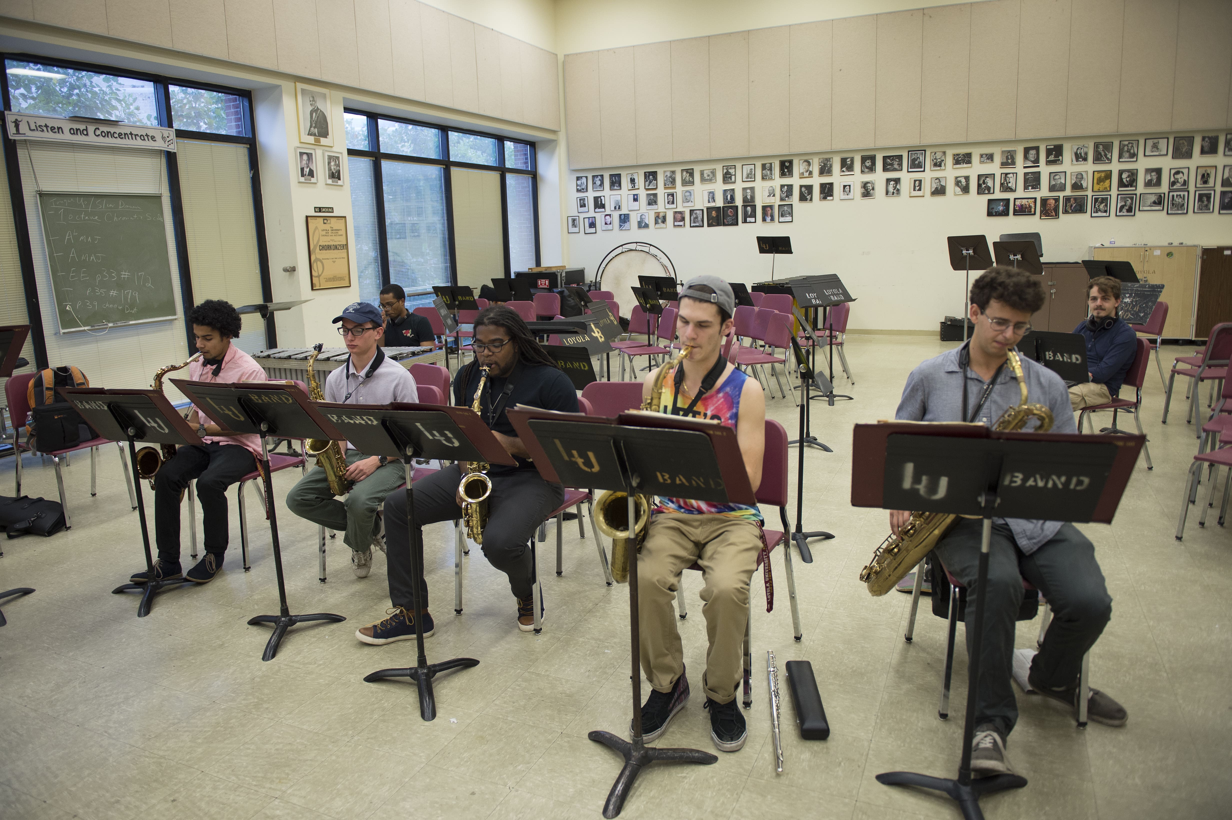 A line of Loyola students playing saxophones of different sizes in rehearsal.