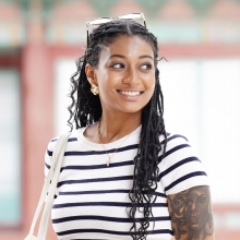 Headshot of Cassidy Wells. She is smiling and looking off to the right. She is wearing a short-sleeved black and white striped t-shirt.