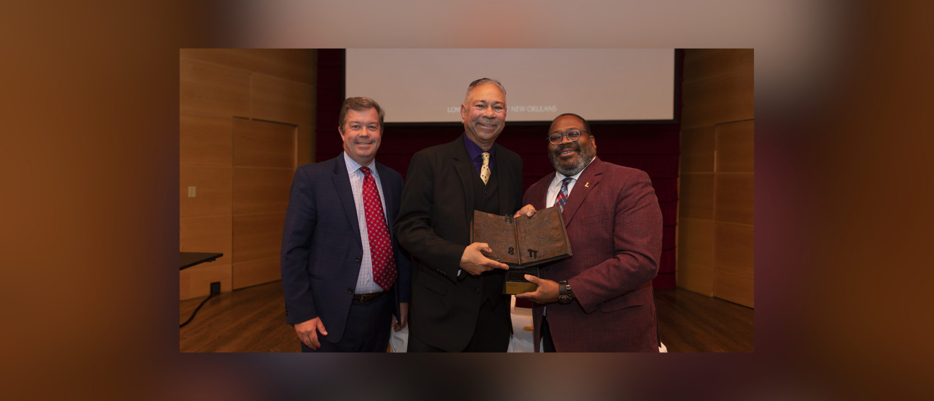 Professor Mitch Crusto accepts the Dux Academicus Award with Loyola President Xavier Cole and Provost Thomas Chambers.
