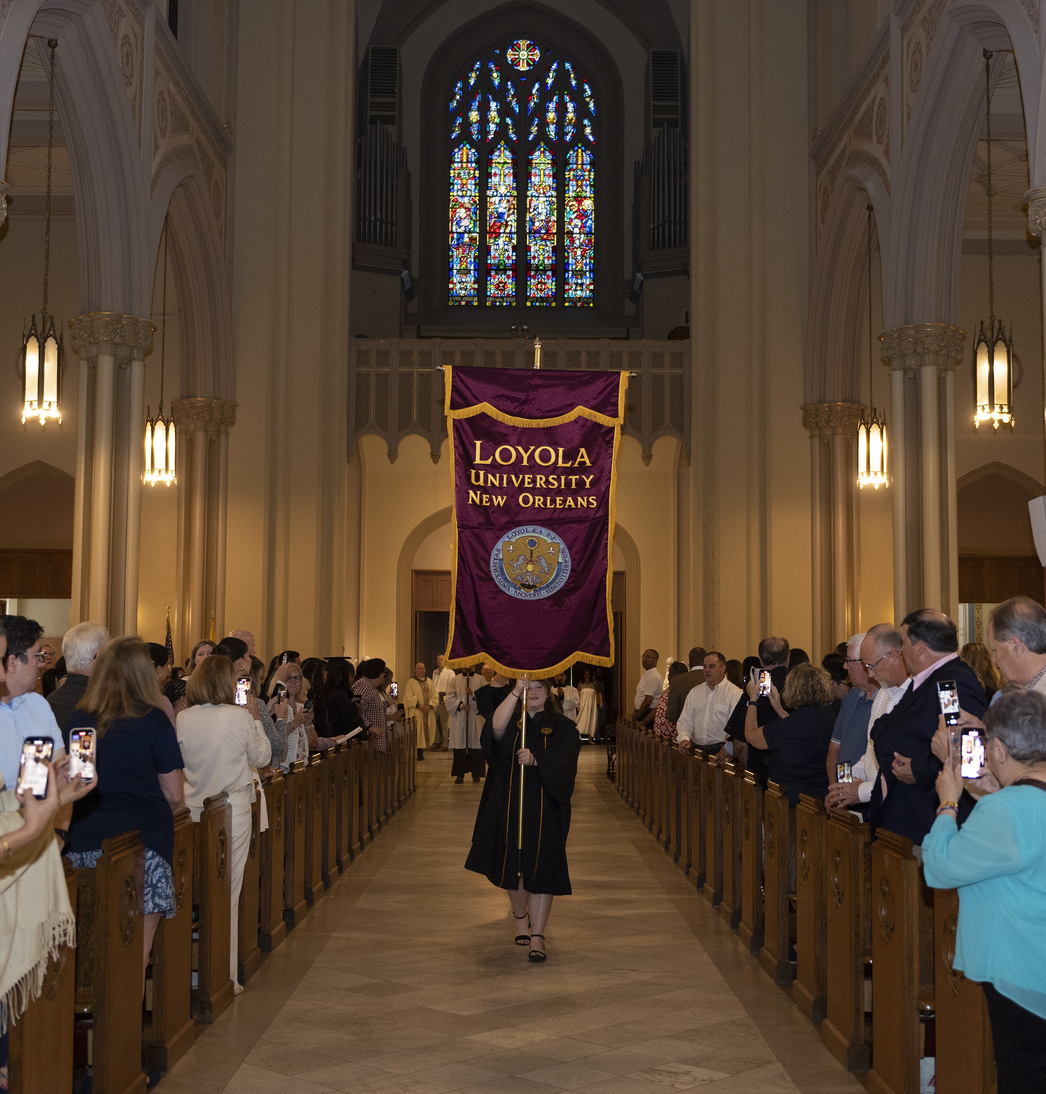 A graduate holding Loyola's banner during a Mass