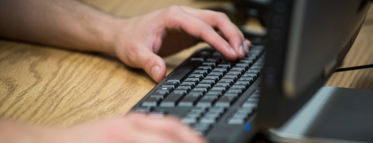 Hands typing on a black keyboard